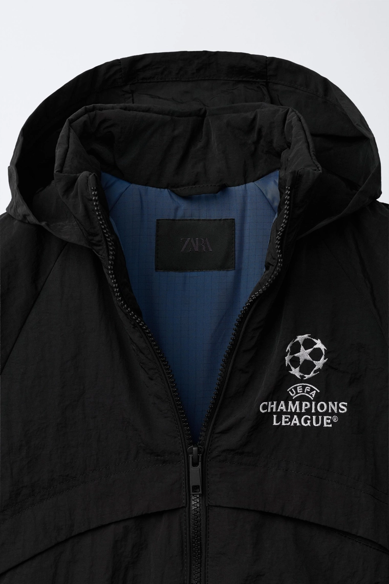 КУРТКА С ПОТАЙНЫМ КАПЮШОНОМ WATER REPELLENT UEFA CHAMPIONS LEAGUE ®